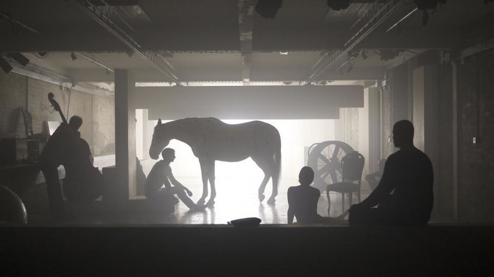 Silhouettes of people with horse, and person holding double bass