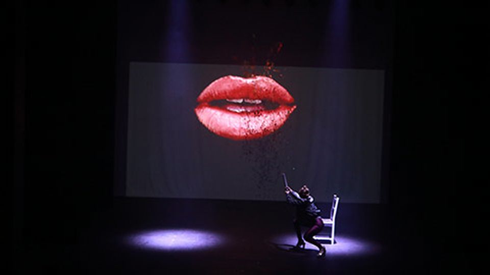 Video projection on stage of lips above student performing