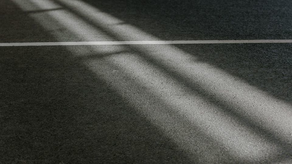 Black and white photograph of lines of light running diagonally left to right across floor with horizontal white stripe