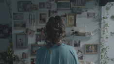 Woman standing in front of wall covered with small hanging pictures