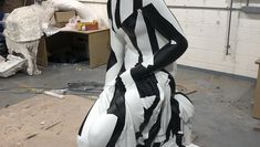 A Greek style sculpture of a woman with black and white stripes painted on