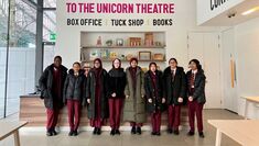 Several Mulberry Arts students in school uniform stand in a line at the Unicorn Theatre