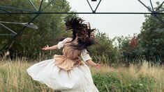 Woman dancing under pylons with mask made of feathers