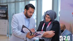 Dr Javeria Khadija Shah reading a conference brochure with fellow attendee of the Education 2.0 conference