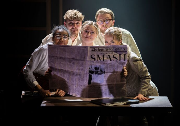 Group of students around a newspaper in a musical production