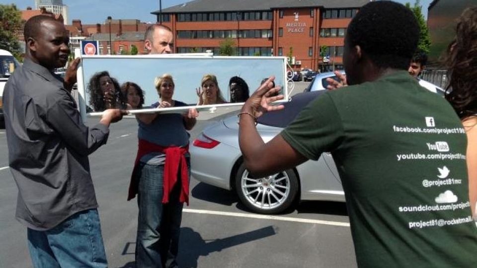 Participants in a parking lot looking into a mirror