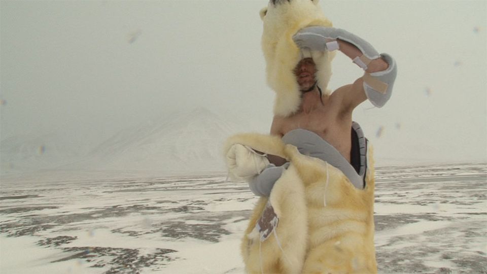 Person emerging from polar bear costume in arctic landscape