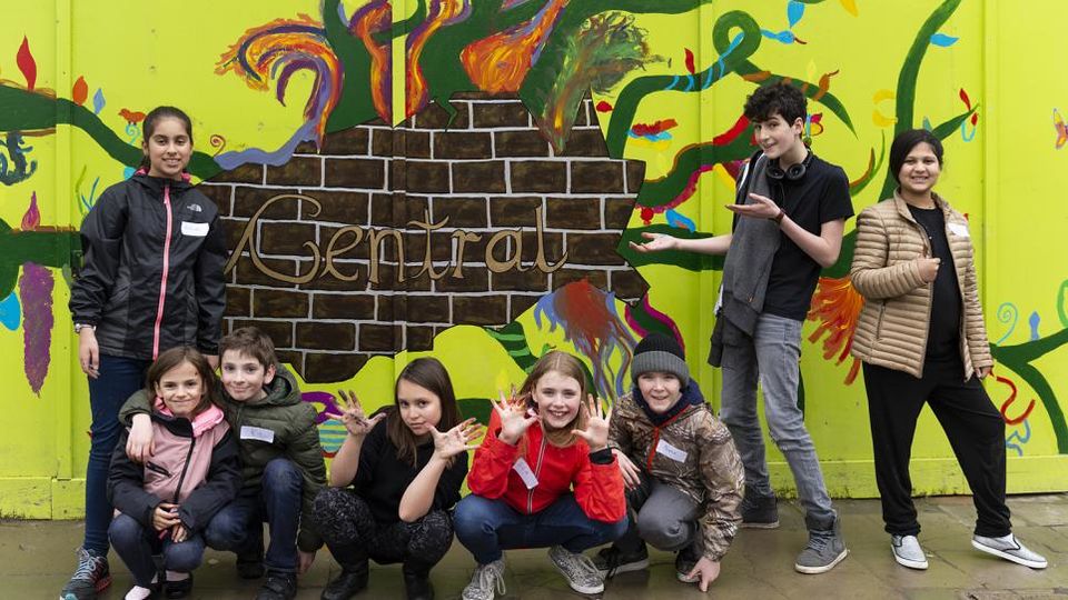 A group of young students in front of a mural that says 'Central'