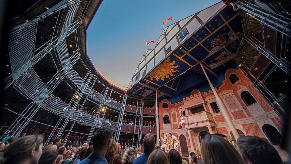 Audience members standing inside Pop-up Globe theatre looking up to the sky