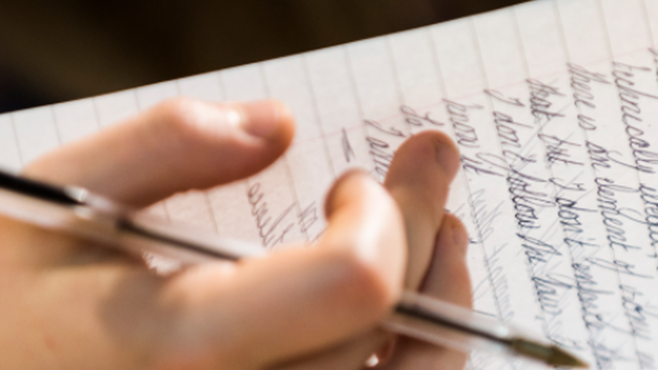 Close up of a hand writing in a notebook