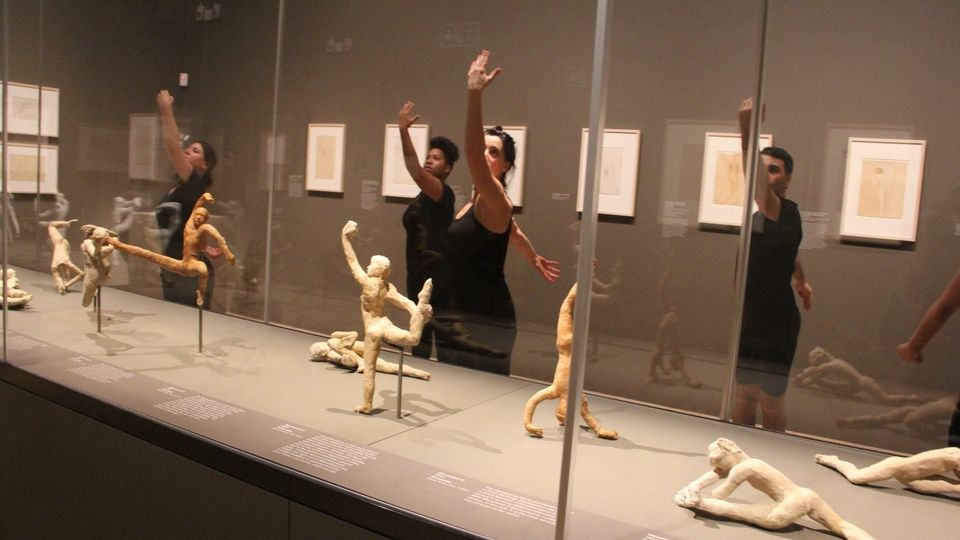 People responding to Rodin sculptures in art gallery