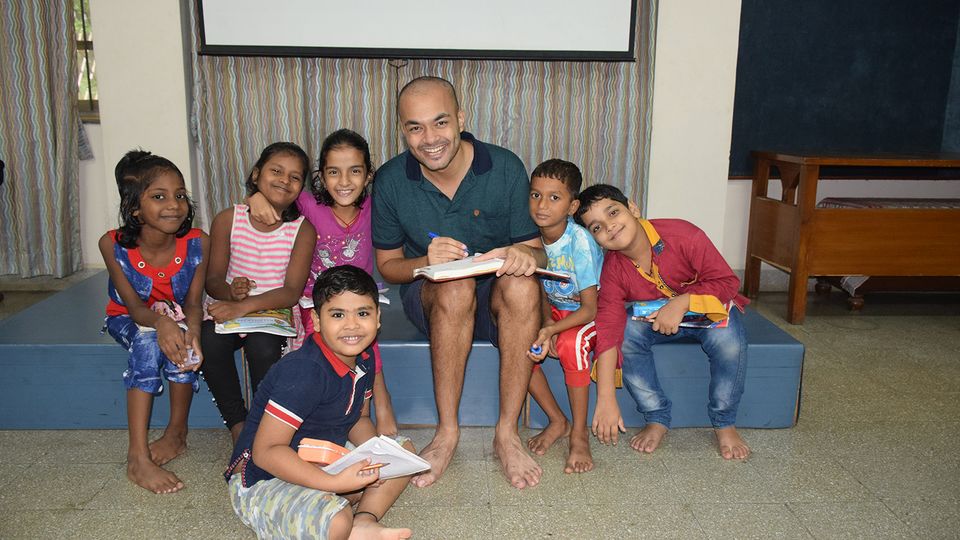 A group of young students smiling with their teacher