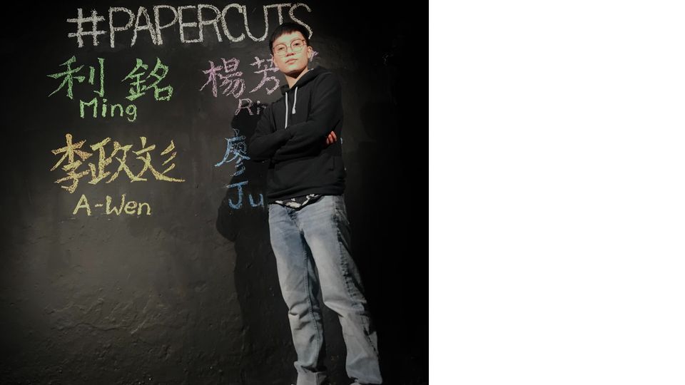 Hector Huang stands in front of a black wall with names written in chalk