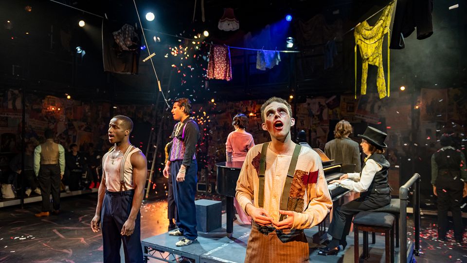 Image from a student production of graduates on stage surrounded by confetti