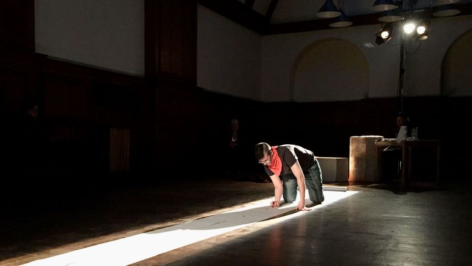 MC Coble on the floor of a performance area, performing the work Timeline of Disruption (2016) at BUZZCUT Festival, Glasgow