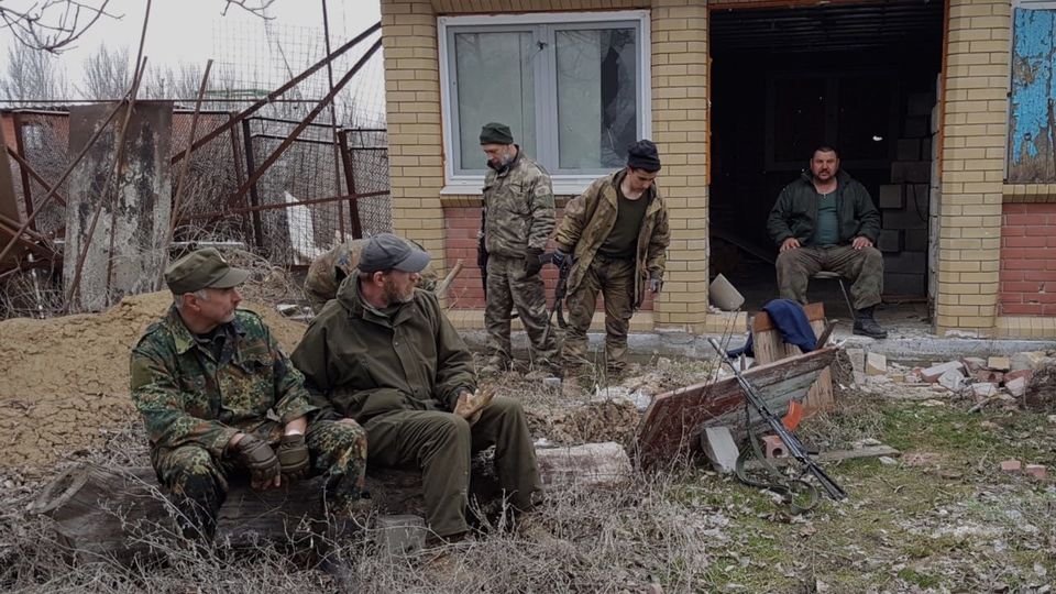 Image showing soldiers in military uniform sitting and waiting outside of a brick building with weapons 