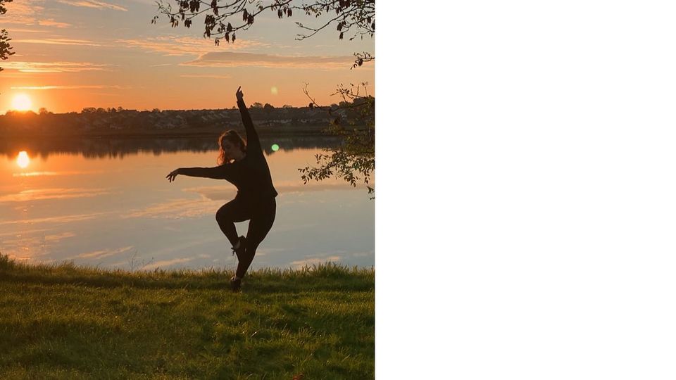 Photo of Meadhbh Lyons in a movement pose on a riverbank with a sunset behind her 