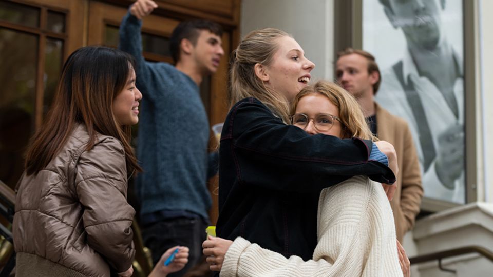 Two female students hug outside Central