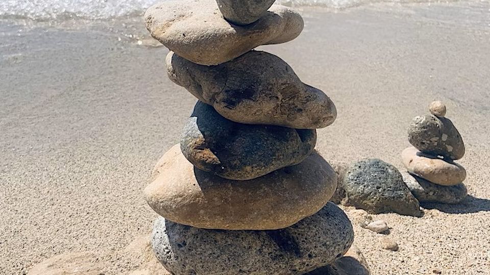Several stones are precariously stacked atop each other on a beach