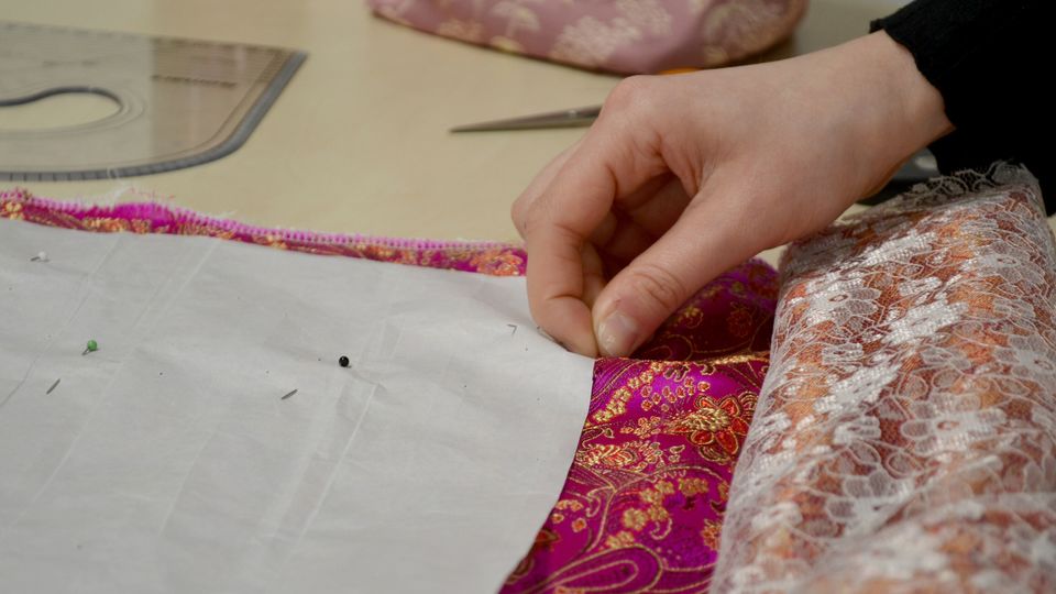 A student pins bright purple and gold fabric