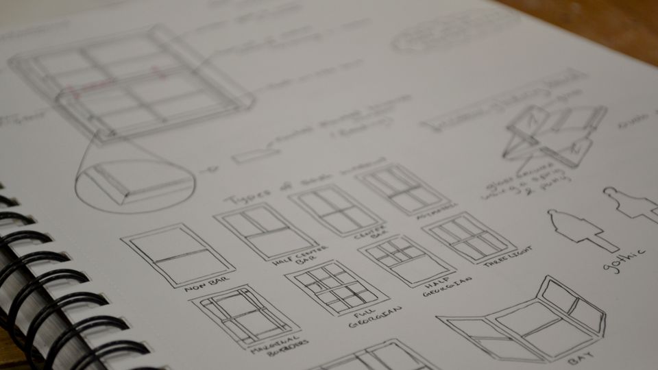 Close up of a sketchbook with black line drawings of different window styles
