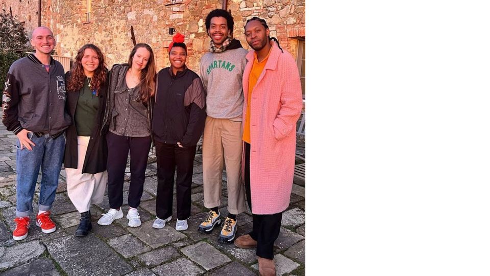 The fellows, including Rianna, standing in a line outside of a brick building in Tuscany