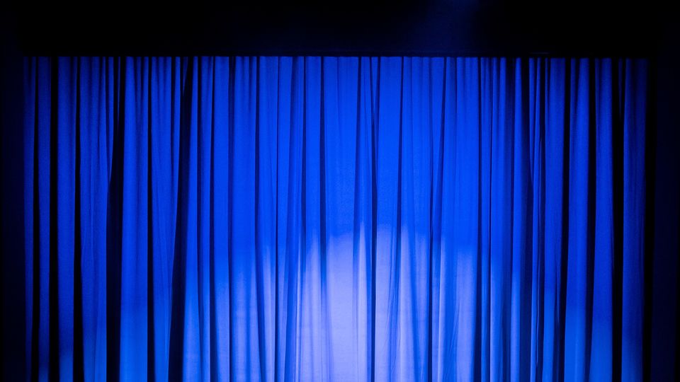 Blue curtains on a stage with a spotlight shining on it