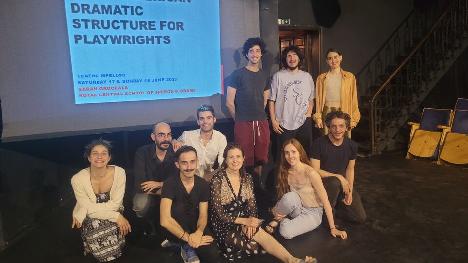 Image of a group of people gathered in front of a screen. Text on the screen reads Anglo-American Dramatic Structure for Playwrights