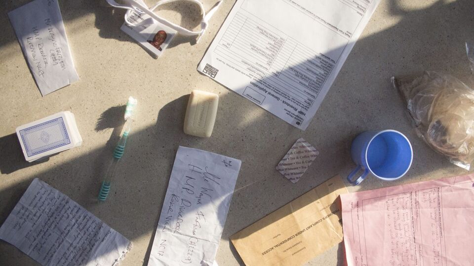 Various items found in a prison, including official papers, a toothbrush and a mug, photographed on a table from above. Taken during Sarah Bartley's collaboration with Rideout called 'Sounding Out' in 2021. 