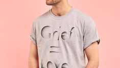 A man wearing a grey tee shirt that says 'grief equals love'