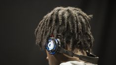 A close up of a person with dreadlocks wearing headphones, facing away from the camera