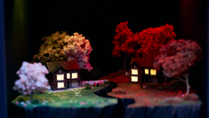 A production still from Behind Closed Doors by theatre company, 27 Degrees showing two model houses surrounded by trees but both separated by an earthquake
