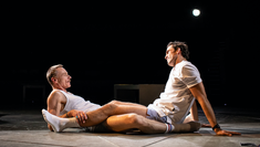 Ben Daniels and Dino Fetscher laying down together on stage in The National Theatre's production The Normal Heart