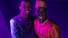 Production still from Netflix's Sex Education, Season 3, showing Ncuti Gatwa as Eric and Jerry Iwu as Oba, showing them embracing each other and smiling. 