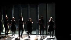Performers in a line run towards a series of doors.