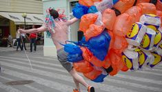 Man running with inflated carrier bags attached to his arms
