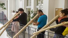4 people standing on a balcony use cardboard tubes like a telescope