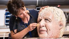 A woman putting the finishing touches on a sculpture of Boris Johnson's head