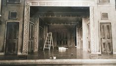 A stage being painted in a theatre, with ladders and tools around