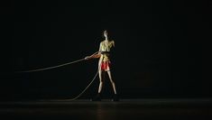 A performer standing legs astride holding a rope