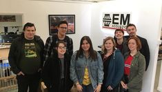8 students face the camera at an EM Acoustics manufacturers 