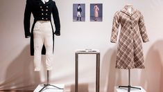 Two costumes in a gallery: a suit and a dress