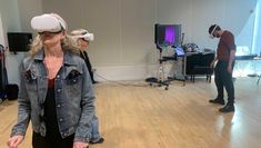 Members of staff standing in a rehearsal space wearing VR headsets