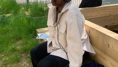 Member of staff sitting on a wooden bench outside wearing a VR headset