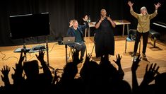 Matthew Mills, Josette Bushell-Mingo and Jane Boston using British Sign Language for applause on stage in front of an audience
