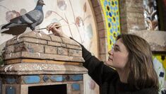 A student adds finishing touches to a prop pigeon, placed within a set