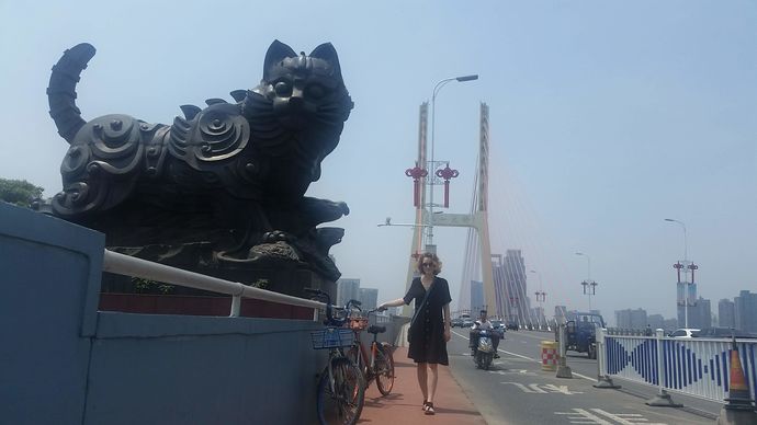 Woman standing on a bridge with a large black cat sculpture