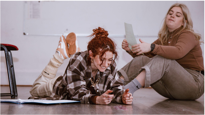 Two actors sitting on the floor, reading lines
