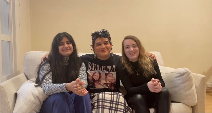 Three people sitting on a couch posing for the camera