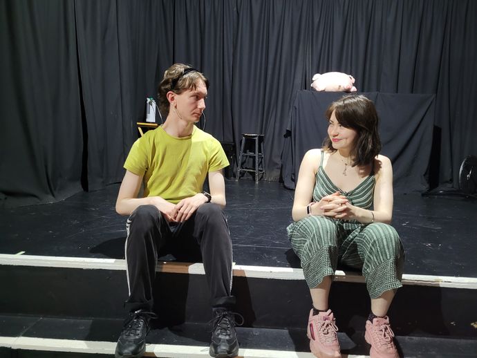 Two actors on stage rehearing a scene while they are sitting down